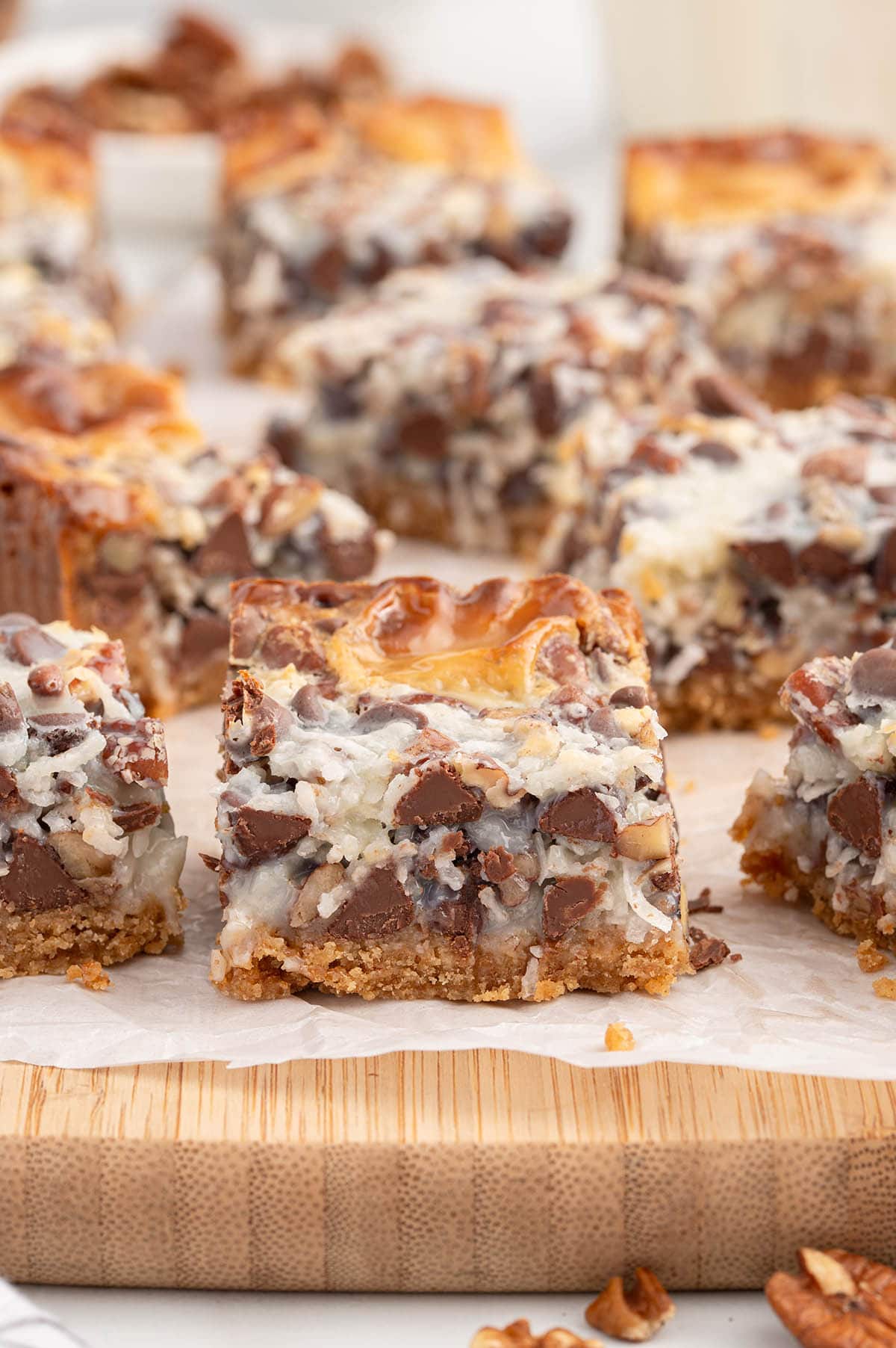 a couple squares of magic cookie bars on top of wooden board. 