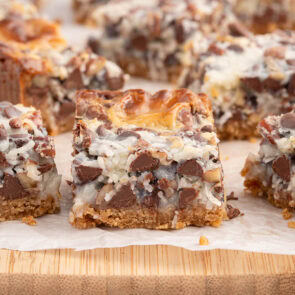 a square piece of magic cookie bars on top of wooden board.