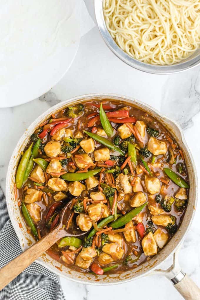 chicken lo mein in a pan with wooden spoon