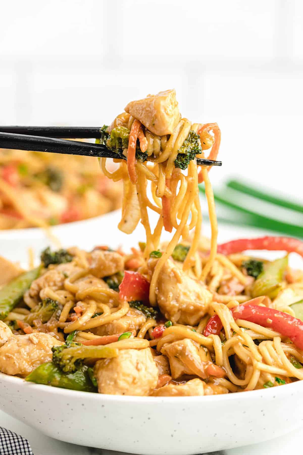 Chicken lo mein with broccoli stir fry served in a white bowl.