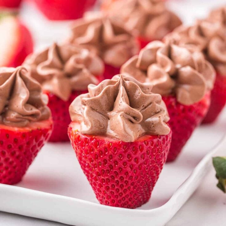 Chocolate cheesecake stuffed strawberries on a white plate.square