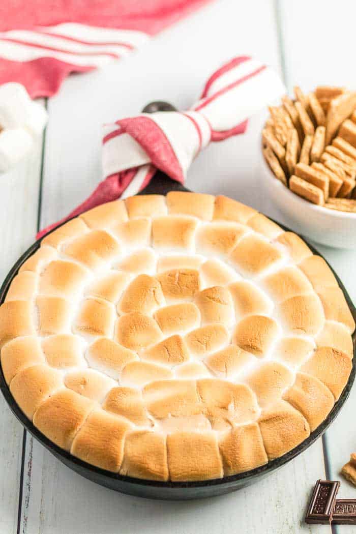 S'mores Dip in a black skillet served with graham crackers in a white cup to the side.