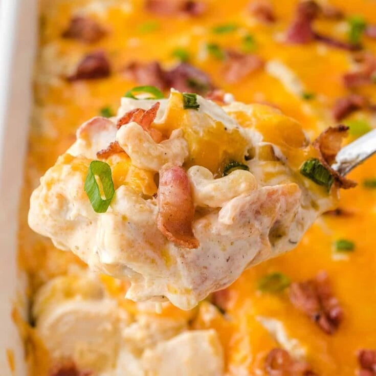 Spoonful of crack chicken casserole with melted cheese, bacon, and green onions.