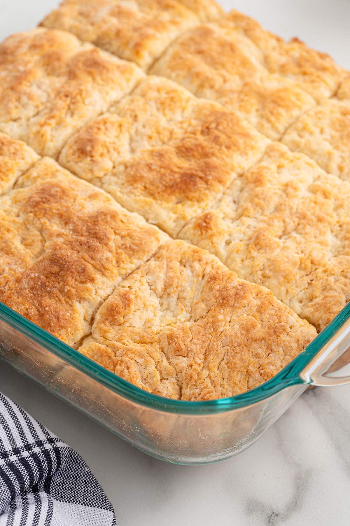 A glass baking dish filled with freshly baked 7UP biscuits with golden tops.