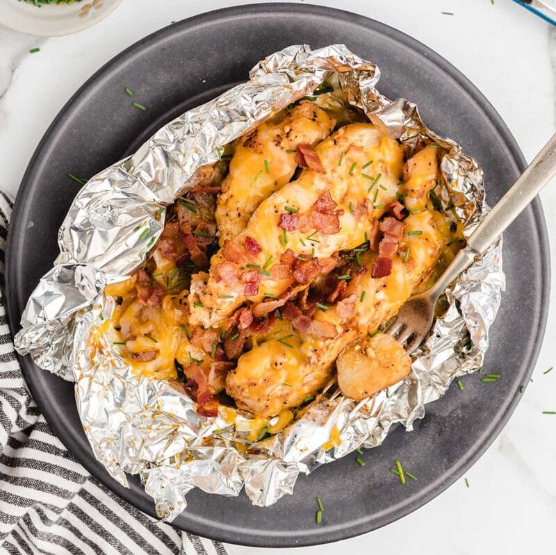 chicken foil packets wrapped in aluminum foil and placed on top of a plate.