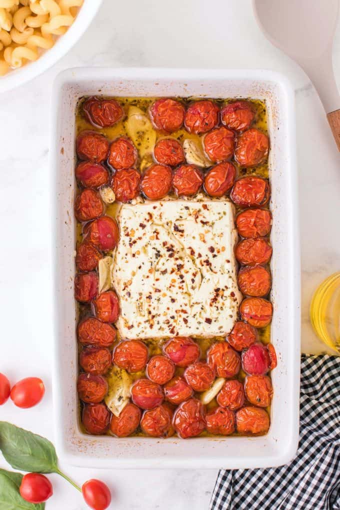 baked tomatoes, feta cheese and garlic cloves in a baking dish