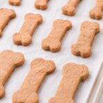 peanut butter dog treats with multiple sizes on top of baking sheet.