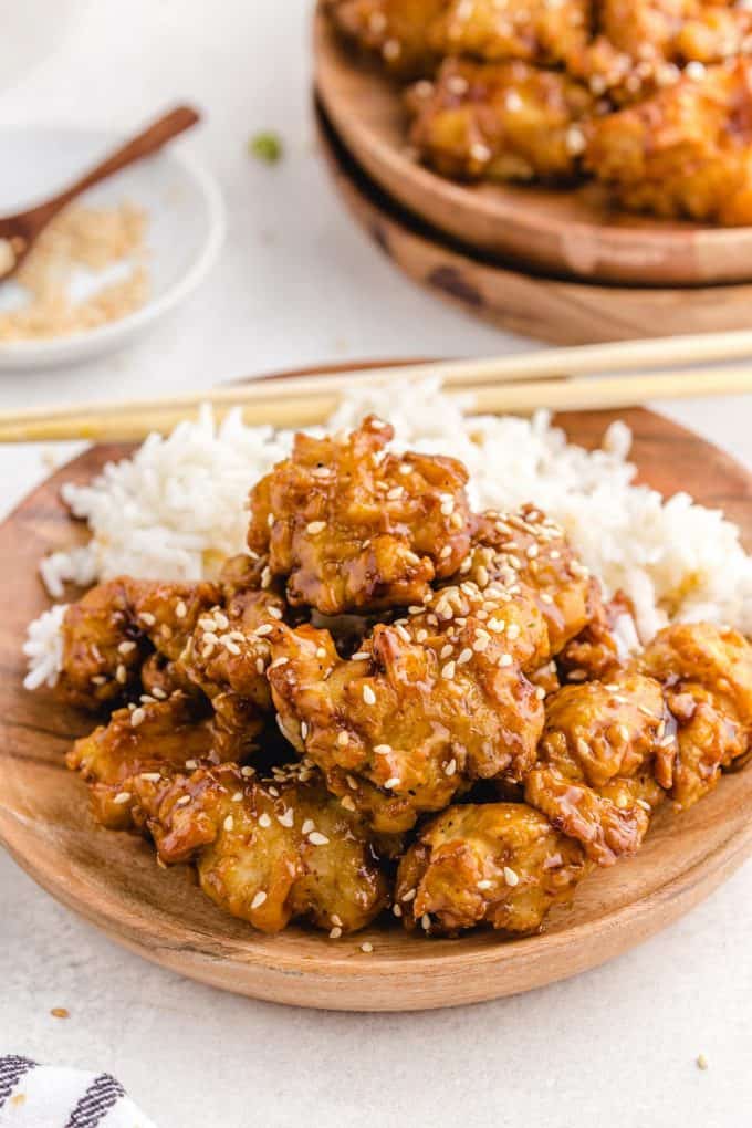 sesame chicken in a plate with rice on the side