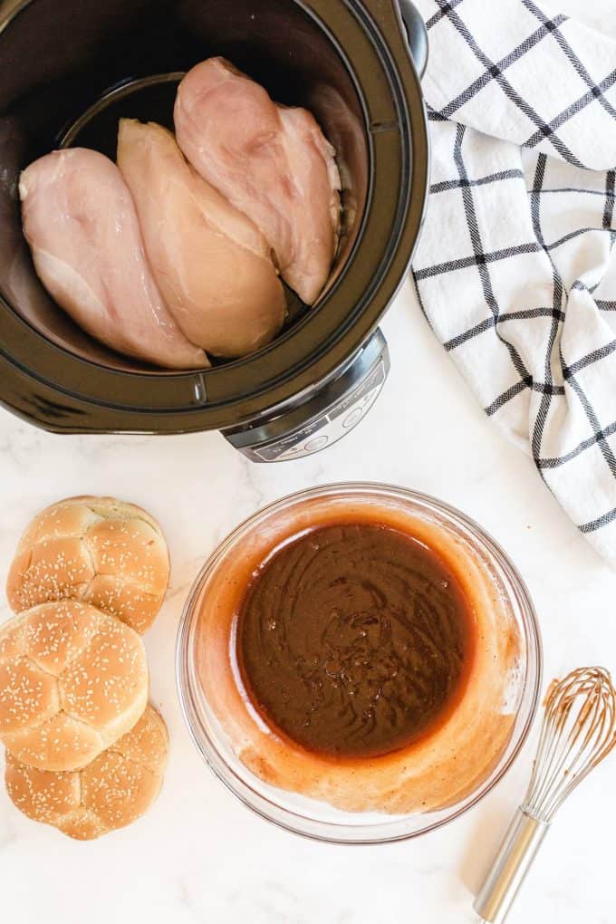 raw chicken inside the slow cooker with sauce on the side
