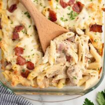 Overhead view of chicken bacon ranch casserole with a wooden spoon in the baking dish.