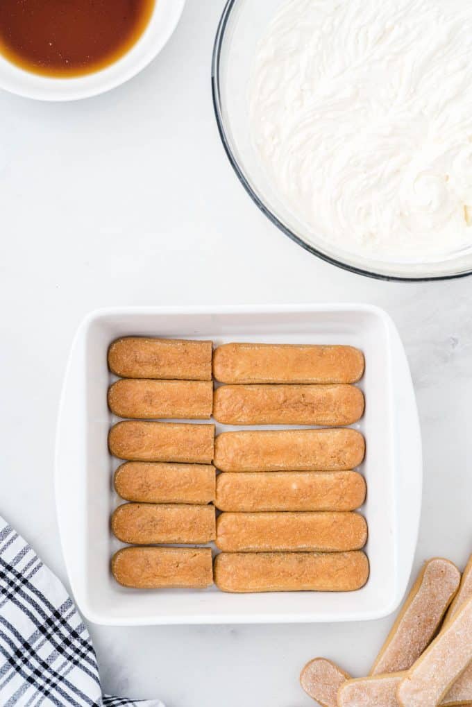 Placing the dipped lady fingers in a single layer in a baking dish