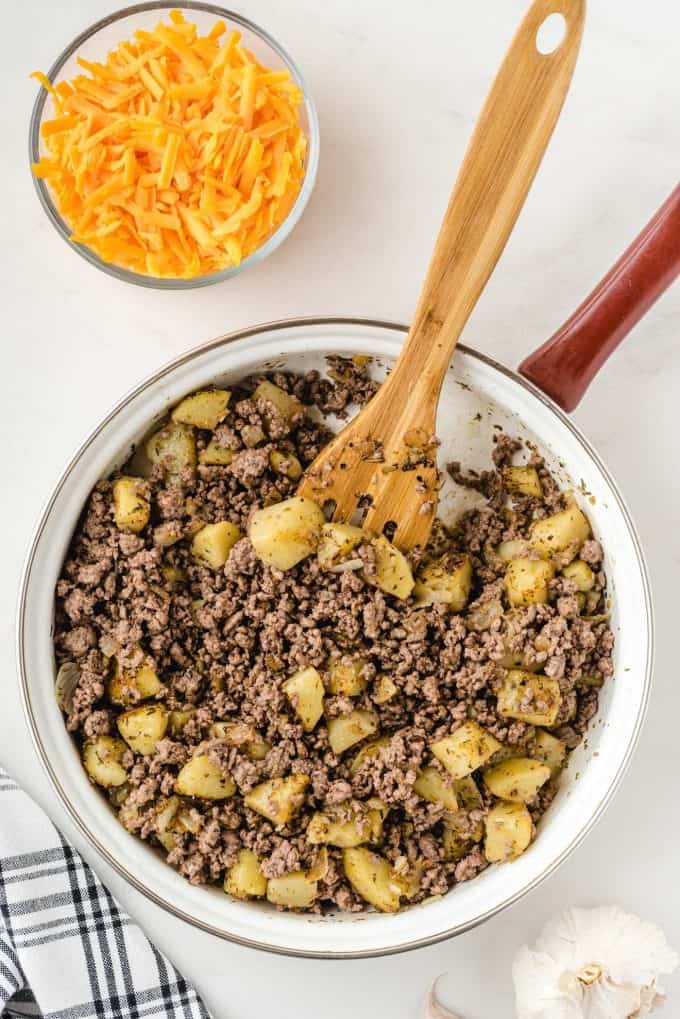 adding ground beef to the pan mix with potatoes
