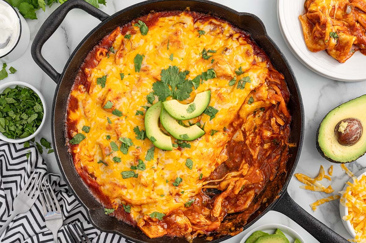 enchilada skillet topped with melted cheese and avocado slices.