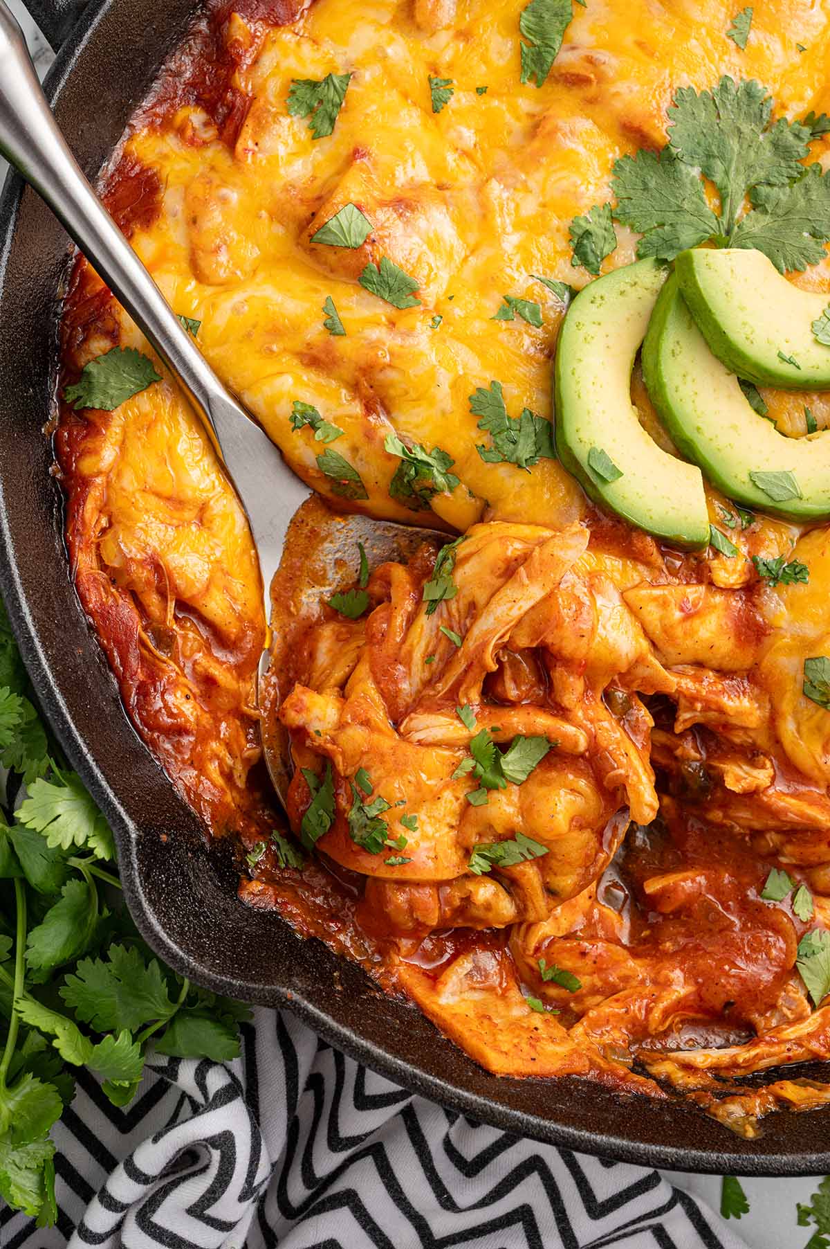 enchilada skillet garnished with fresh cilantro and avocado slices.