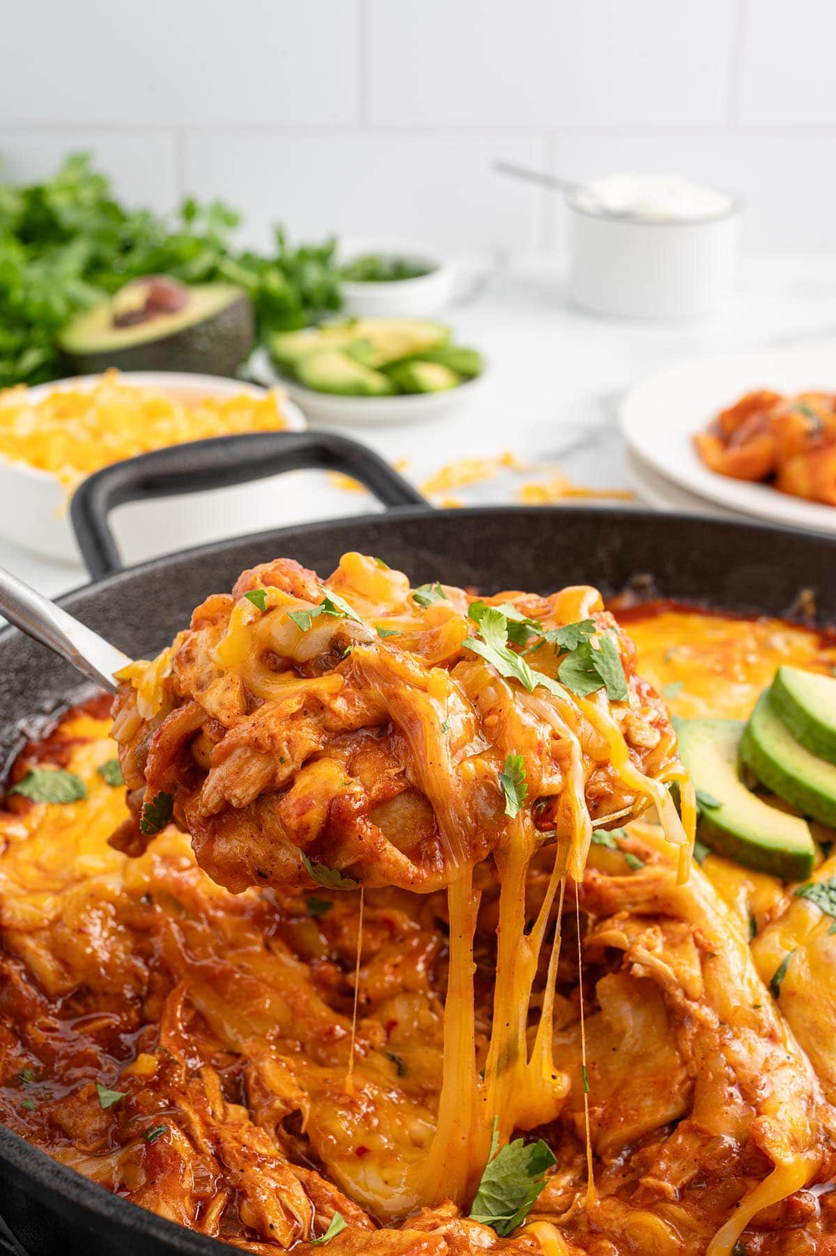 a spoon lifts a portion of enchilada skillet.