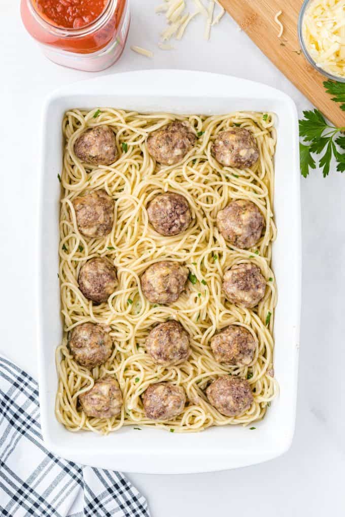 placing meatballs on top of the noodles inside baking dish