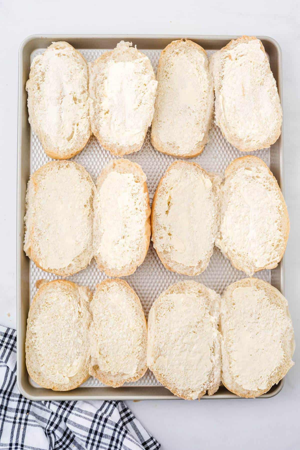 butter on hoagie buns on top of baking sheet