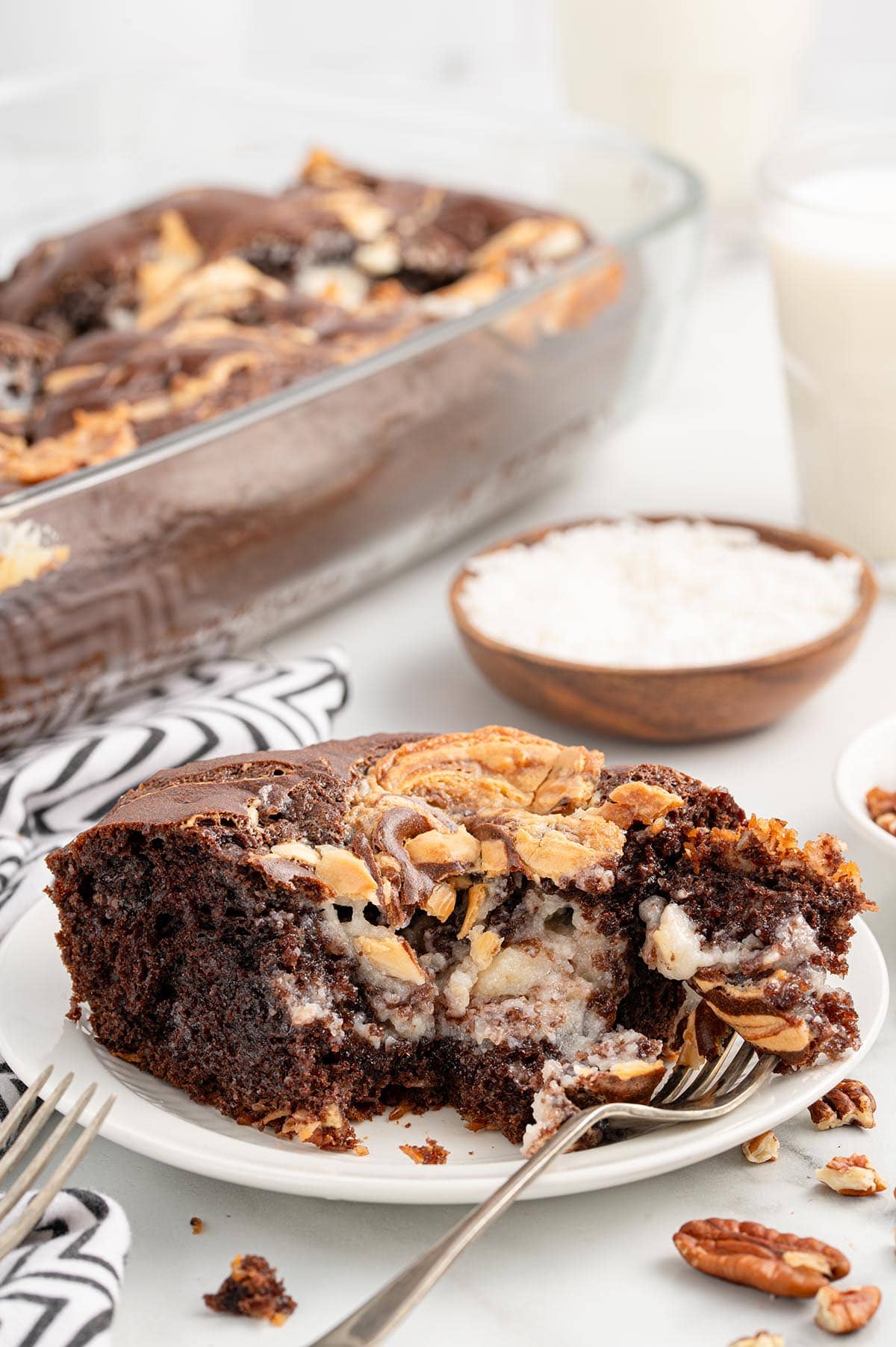 A slice of Earthquake Cake served on a plate with the full cake dish in the background.