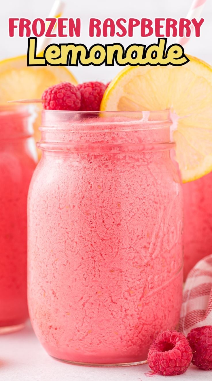 Bright Frozen Raspberry Lemonade inside a mason jar decorated with raspberries and a slice of lemon.