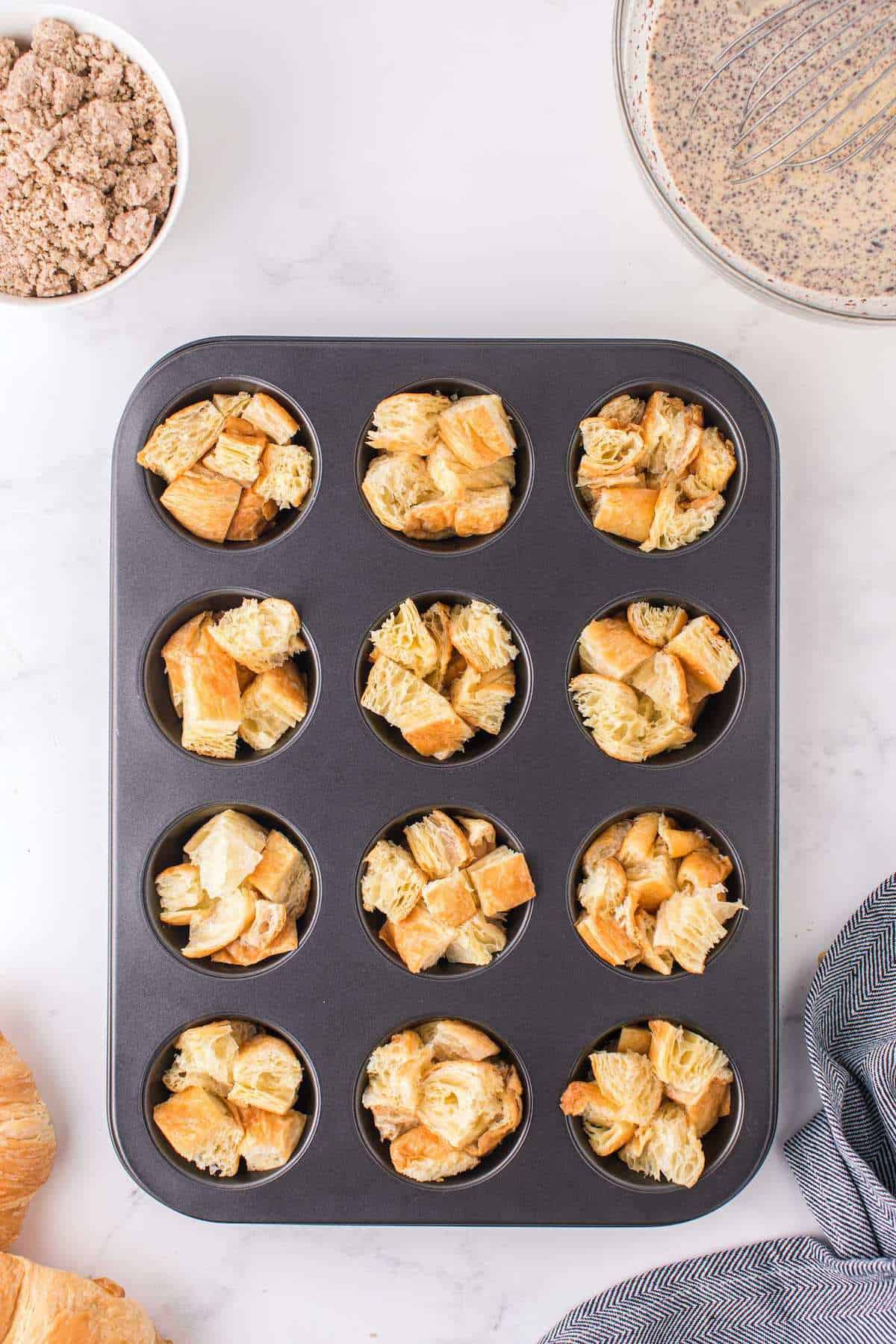 small cubes of croissant inside muffin tins