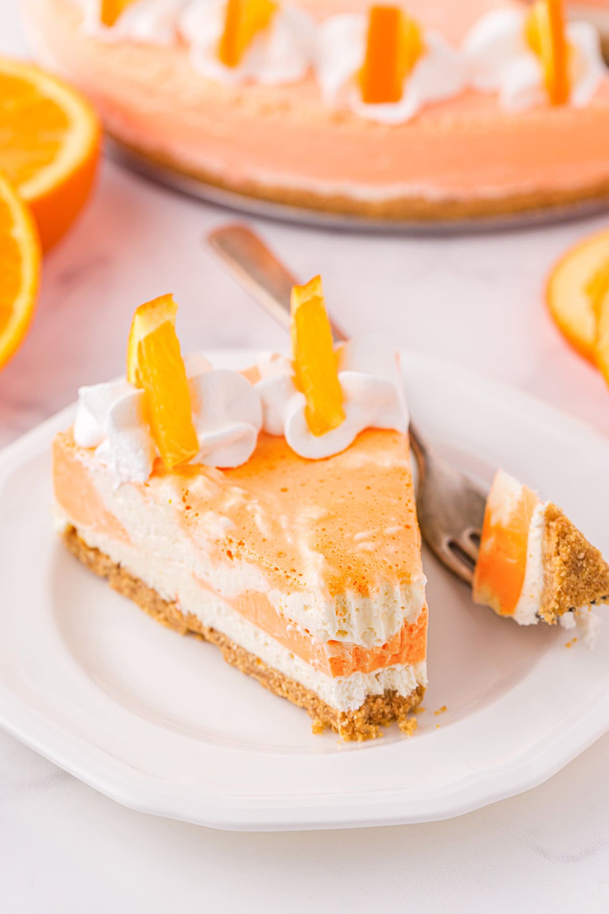 eating a slice of orange creamsicle cheesecake on a plate. 