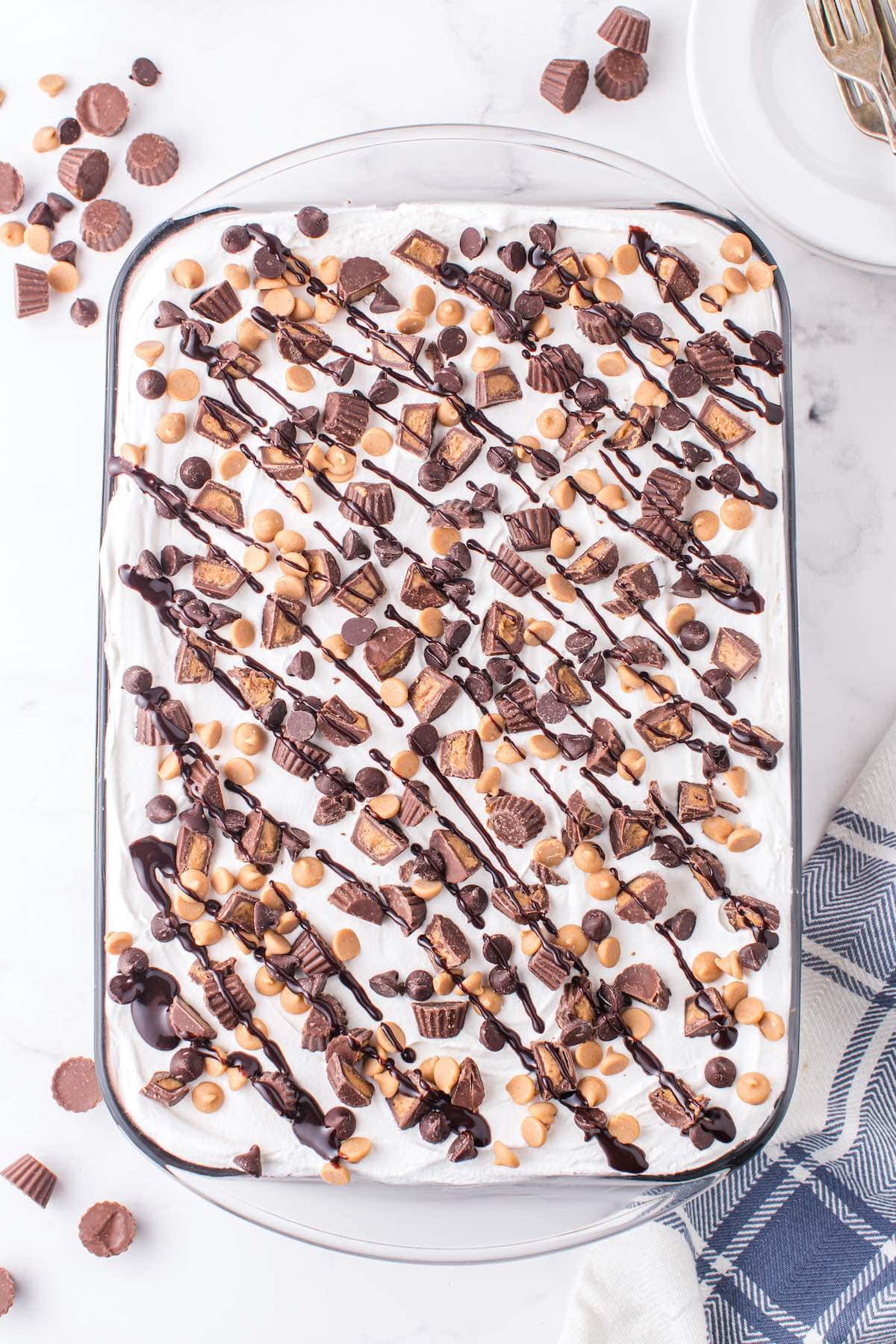 Top with whipped topping, peanut butter chips, chocolate chips, Reese’s cups and syrup