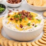 crack dip in a bowl topped with shredded cheese.