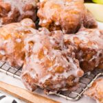 a couple of apple fritters on top of wooden board.