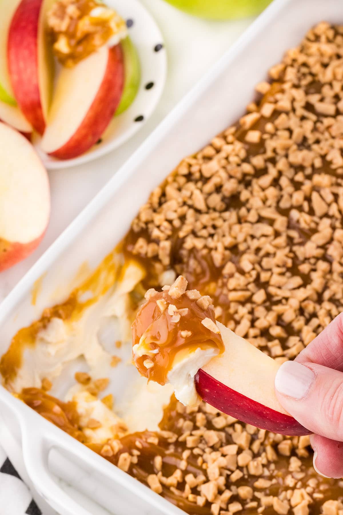 dipping a slice of apple into caramel apple dip. 