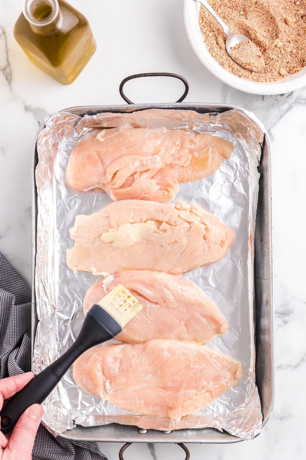 Using a pastry brush, brush both sides of the chicken pieces with olive oil.