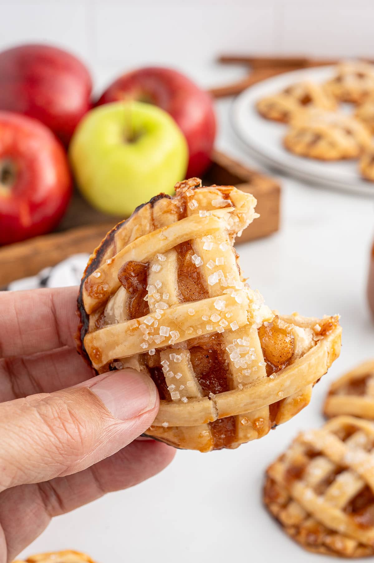 a hand holding a bitten apple pie cookies.