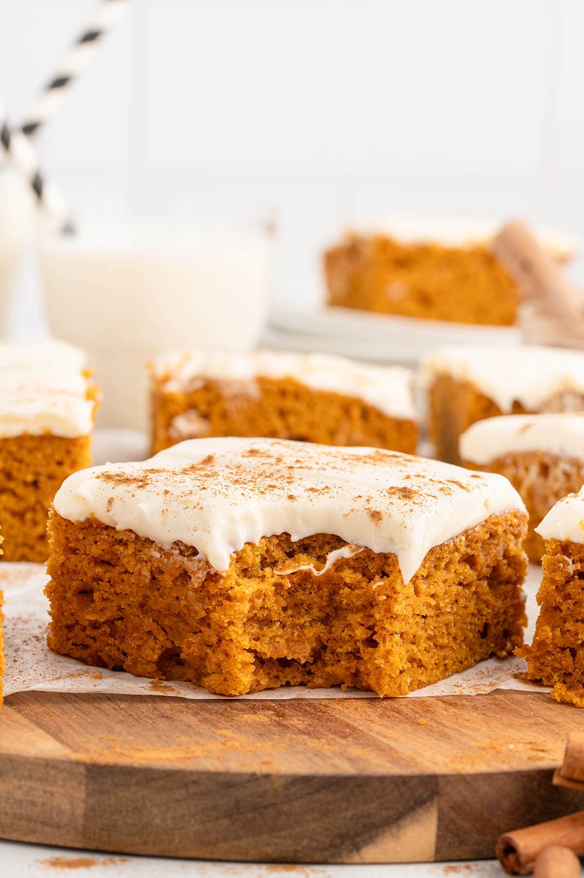 a couple of Pumpkin Bars on a wooden board sprinkled with cinnamon powder.