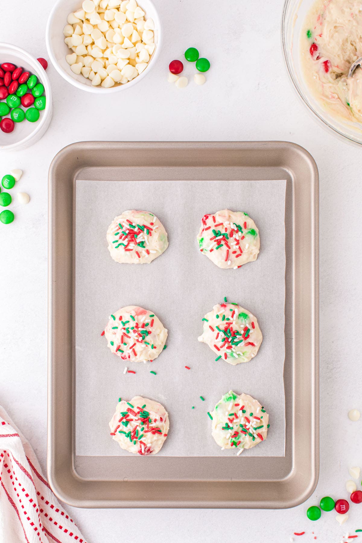 Scoop cookie dough onto sheet pans and coat the top of each cookie with sprinkles