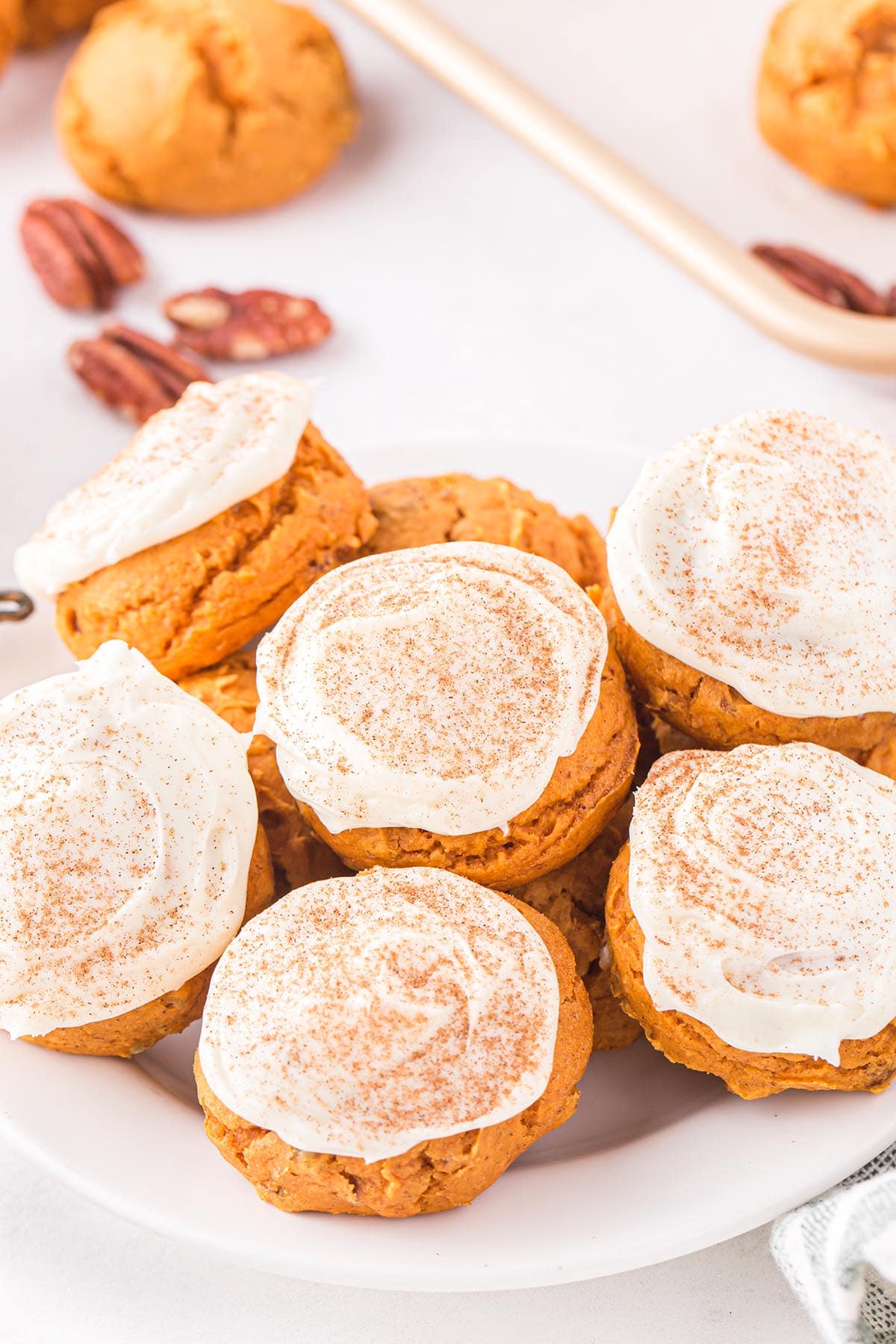 a couple of Pumpkin Cake Mix Cookies on a plate with frosting on top.