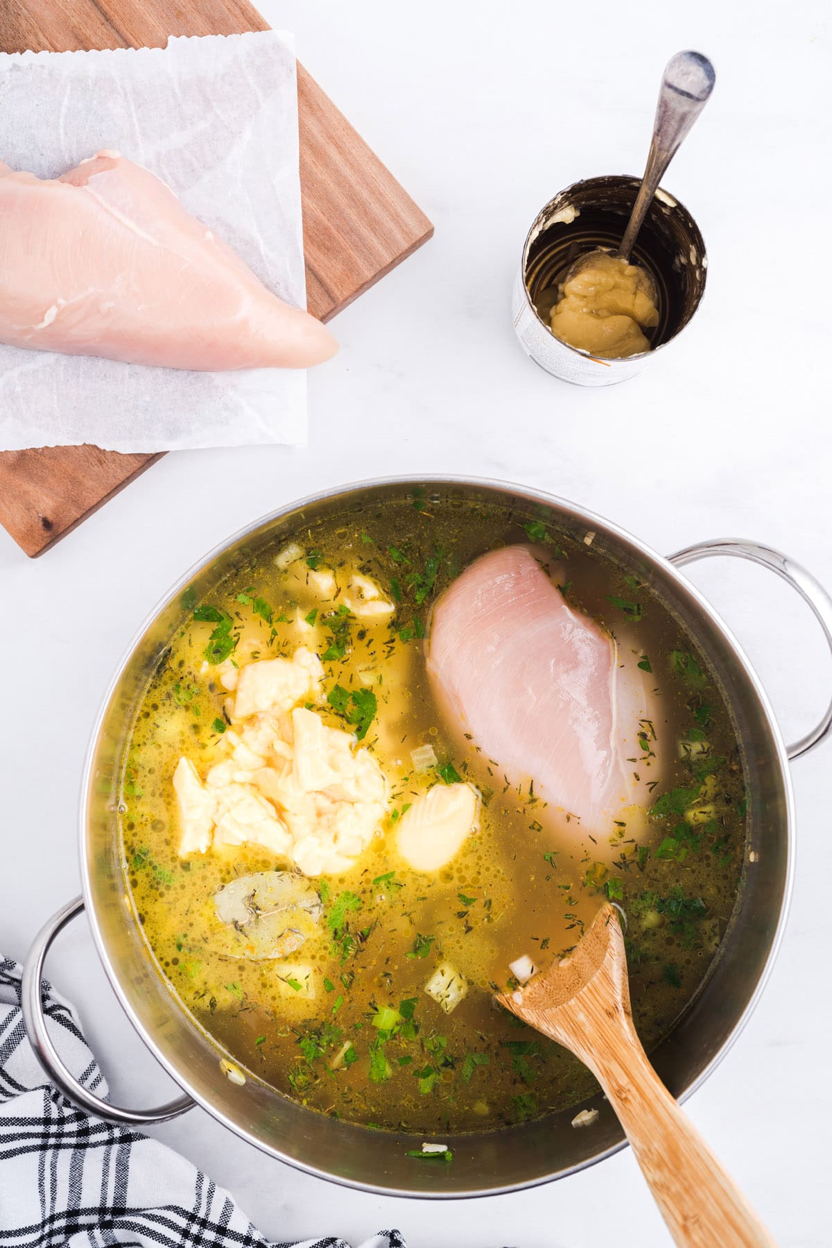 Add chicken broth, cream of chicken soup, and raw chicken breasts