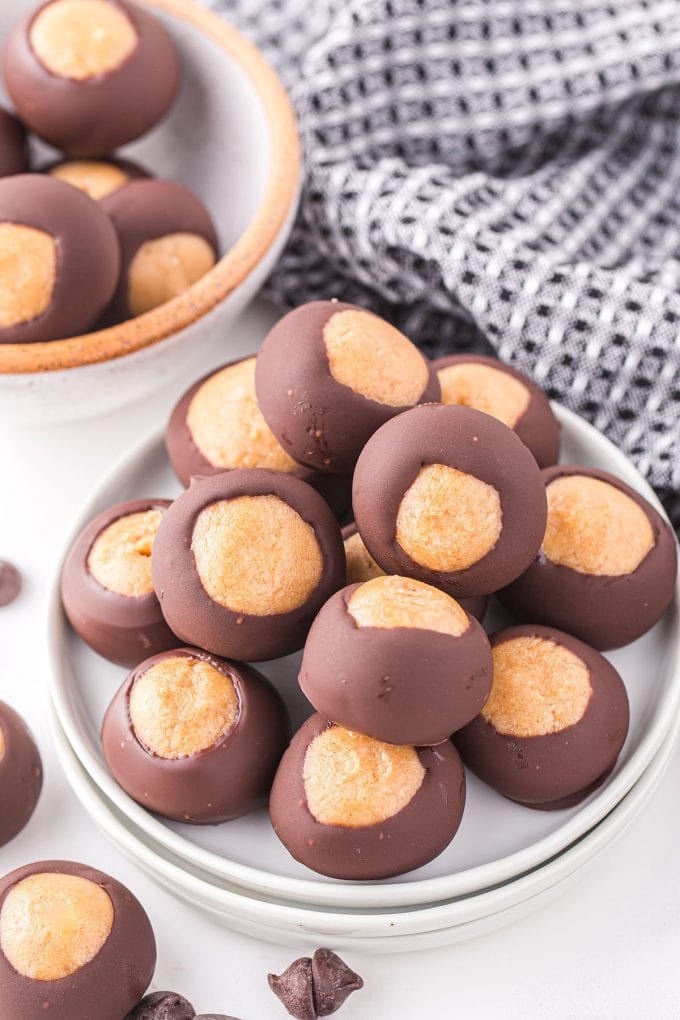 A plate stacked with homemade buckeye candies featuring peanut butter centers and chocolate coatings.