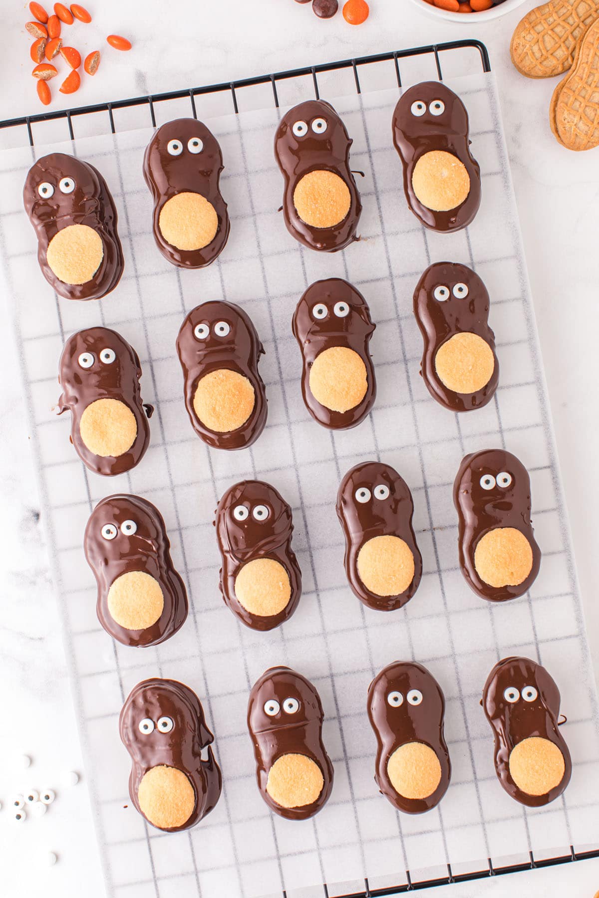 Add two candy eyes to the top half of each cookie