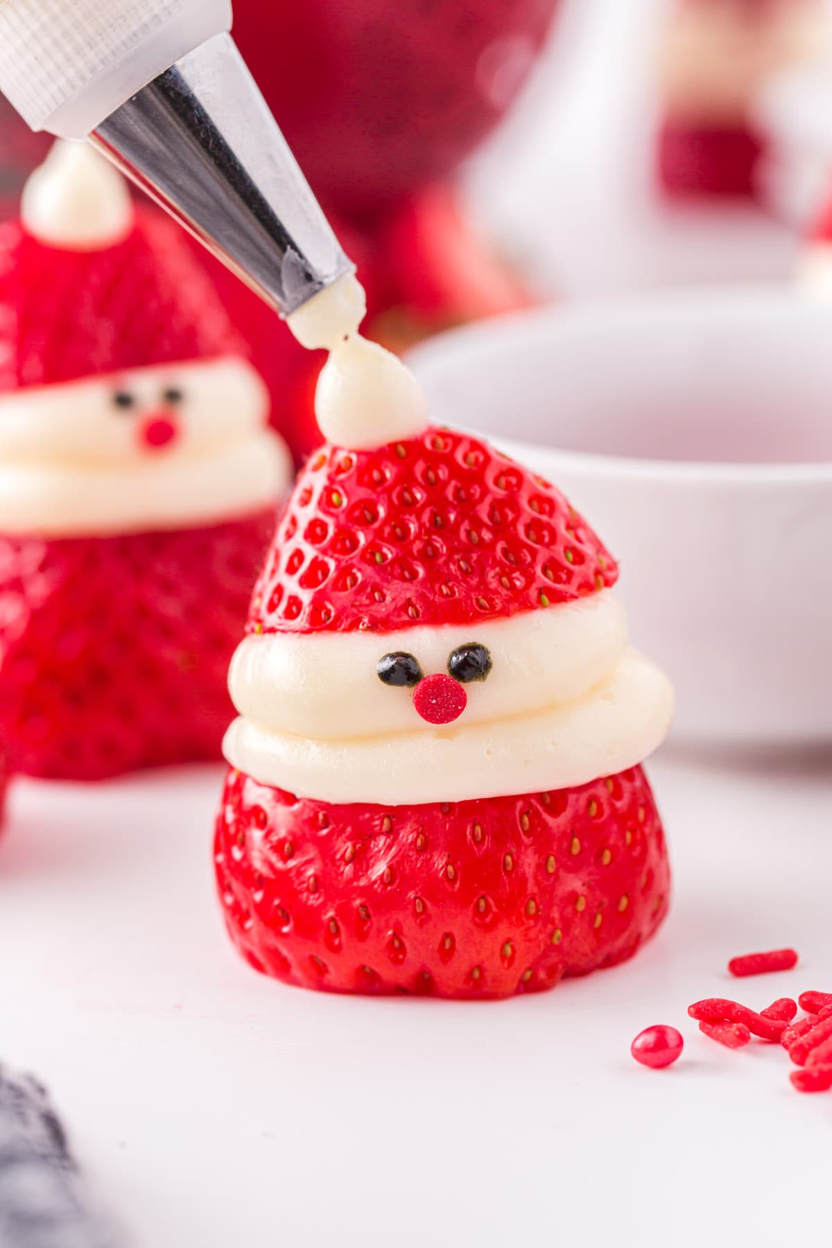Top each swirl with a Santa hat and pipe a dot of frosting onto the tips of each hat to create the pom pom