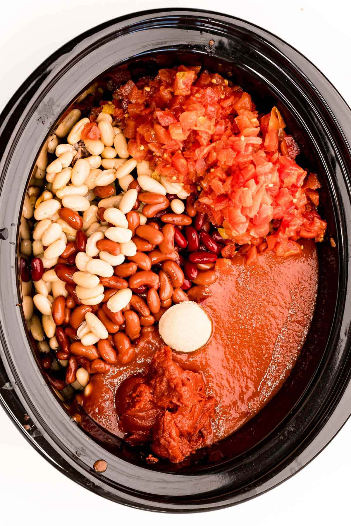 Add diced tomatoes, tomato sauce, tomato paste, beans, and beef stock to the slow cooker
