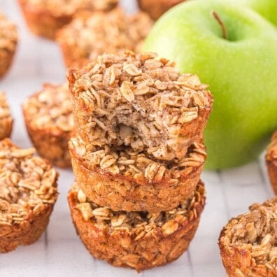 Stack of baked oatmeal cups with a green apple in the background.
