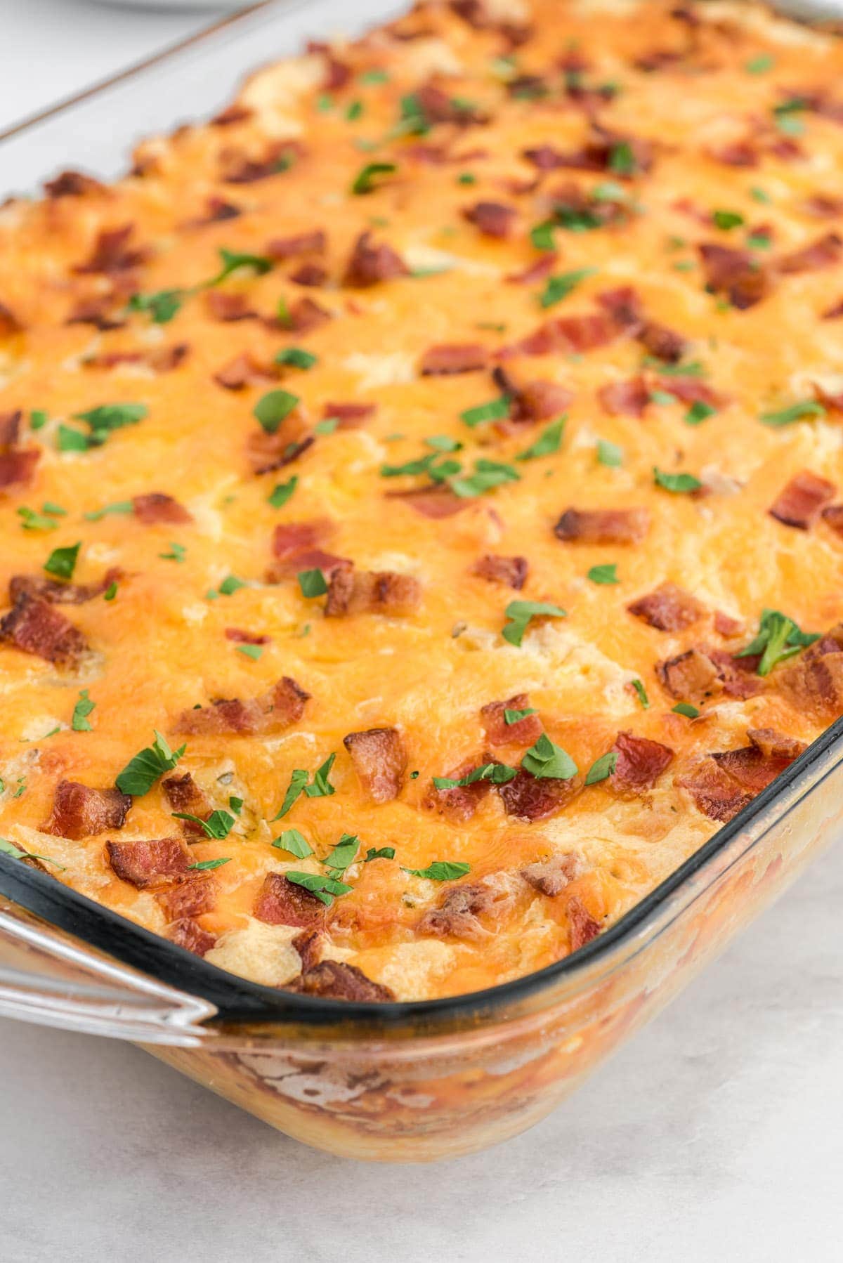 crack potatoes topped with bacon in a casserole dish. 