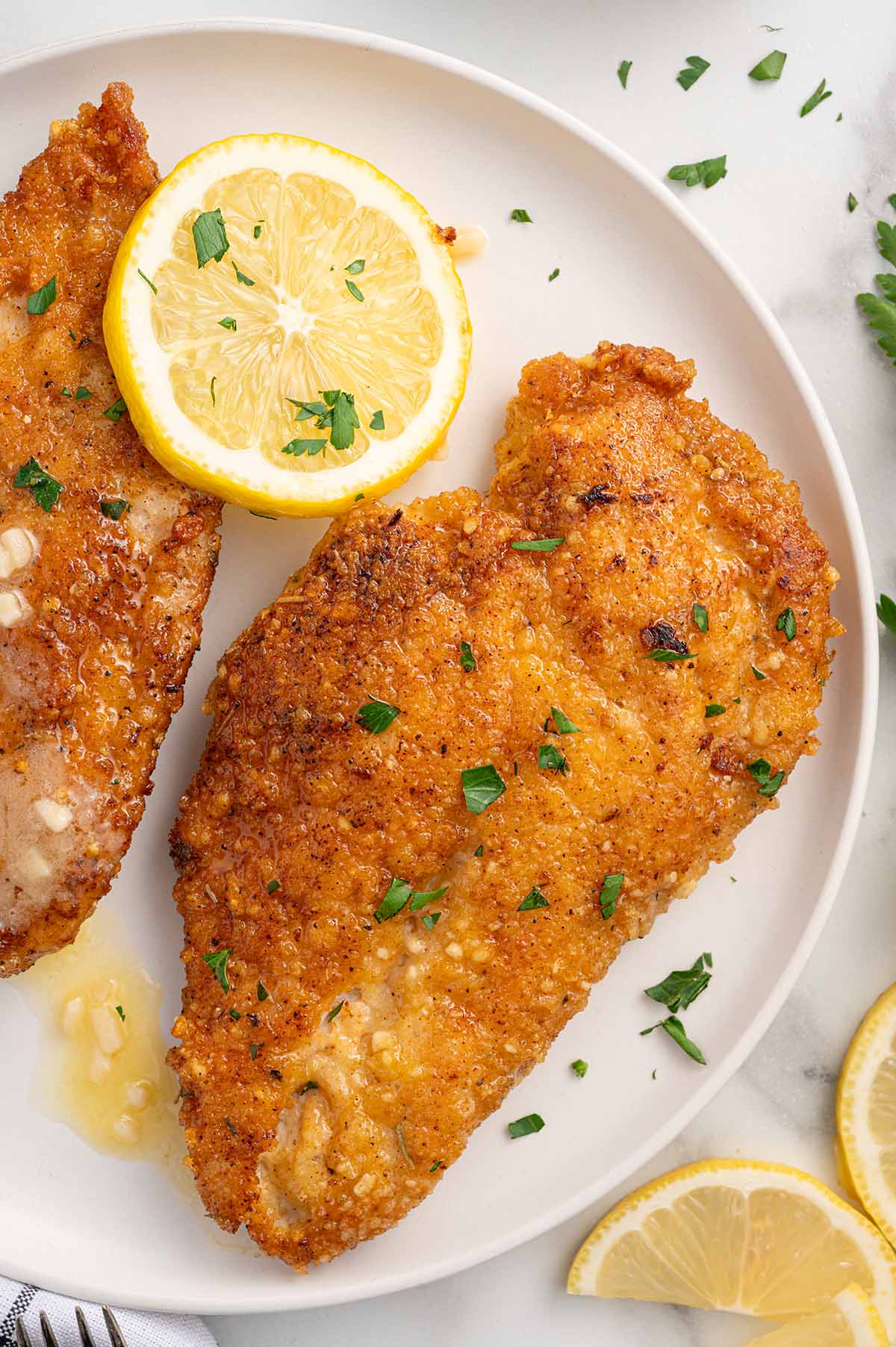 Crispy lemon chicken garnished with parsley and fresh lemon slices.