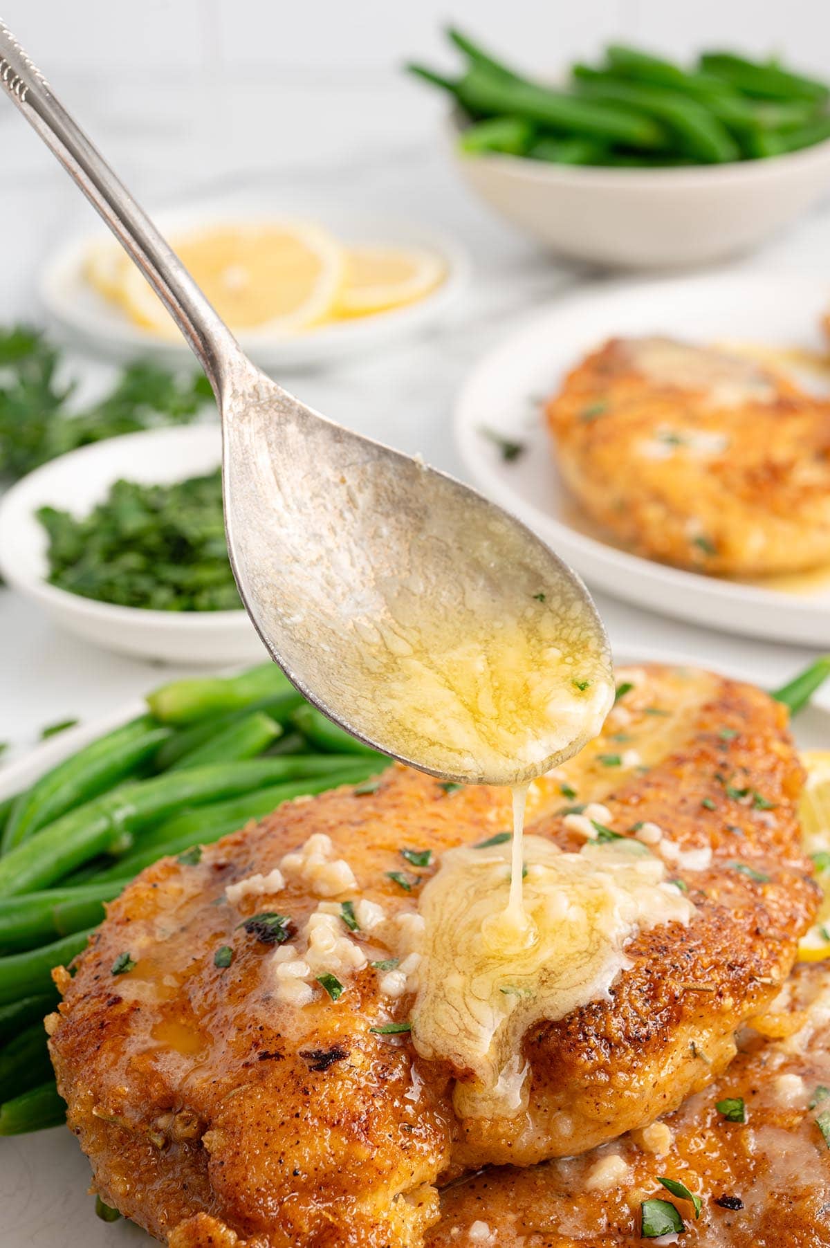 Buttery lemon sauce drizzling over crispy chicken with garlic and parsley.