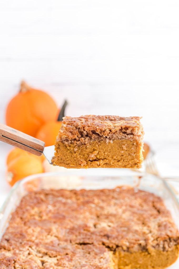 a slice of Pumpkin Dump Cake taken out from the casserole dish using spatula. 
