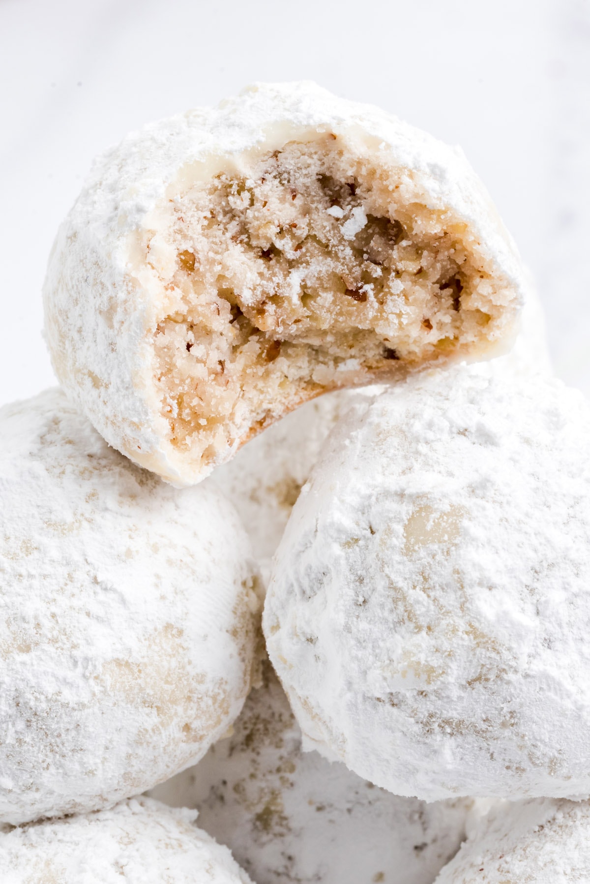 close up of snowball cookies with one  having a bite.