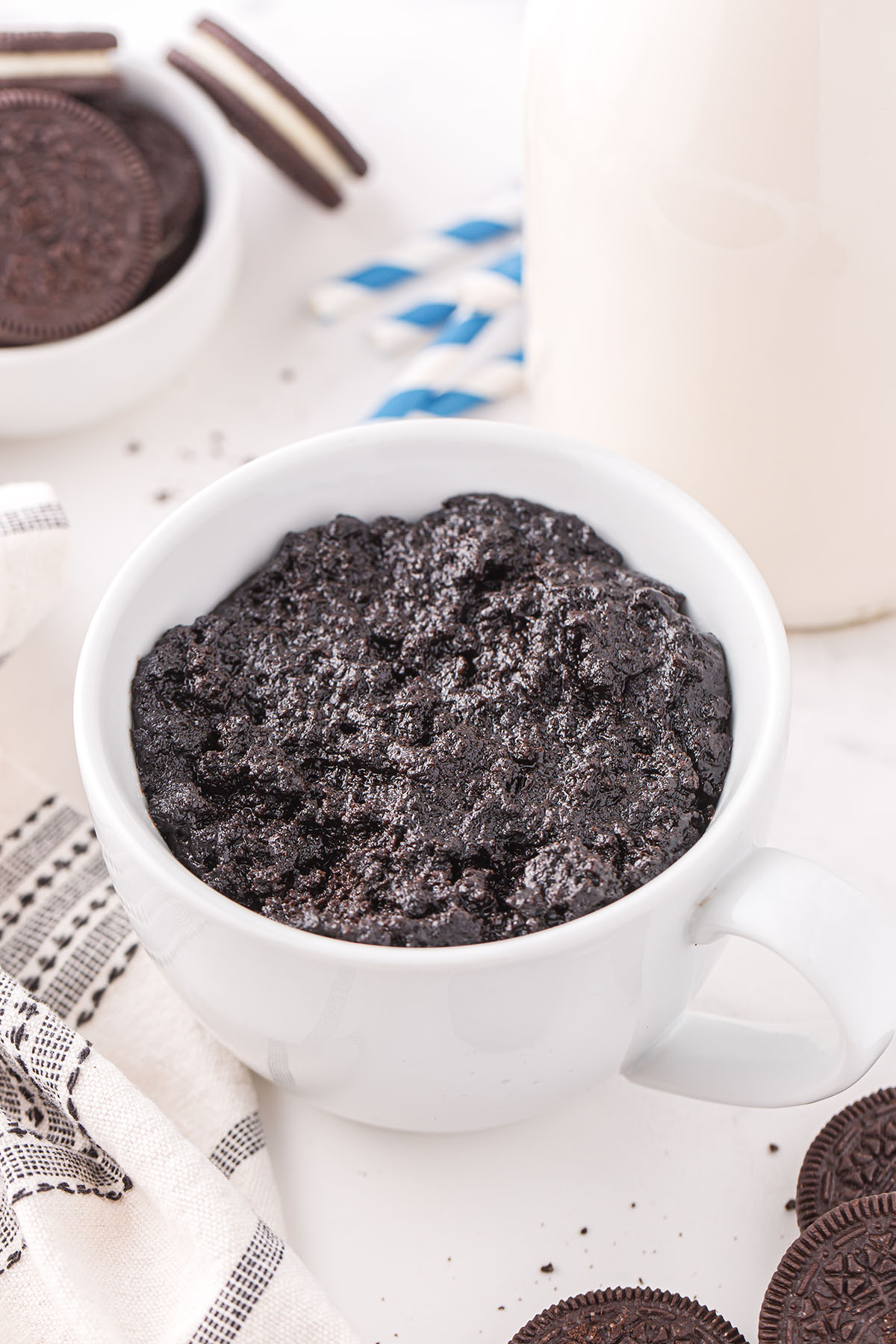 A close up of a coffee cup on a plate, with Oreo and Cake