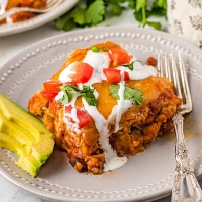 Beef enchilada casserole topped with sour cream, tomatoes, and cilantro.