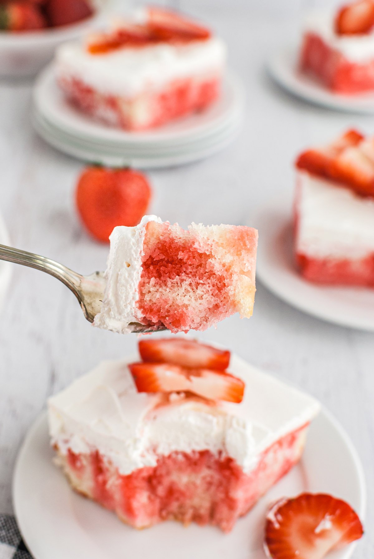 eating strawberry jello poke cake with fork.