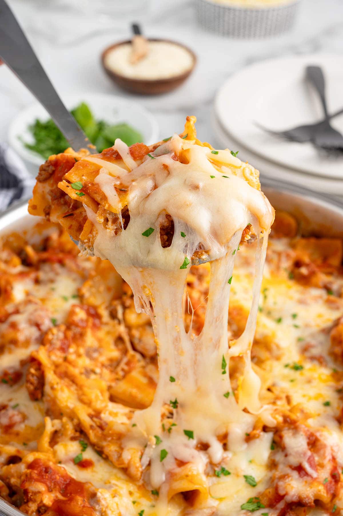 Cheesy skillet lasagna with a spoon lifting a gooey, cheese-stretching serving.