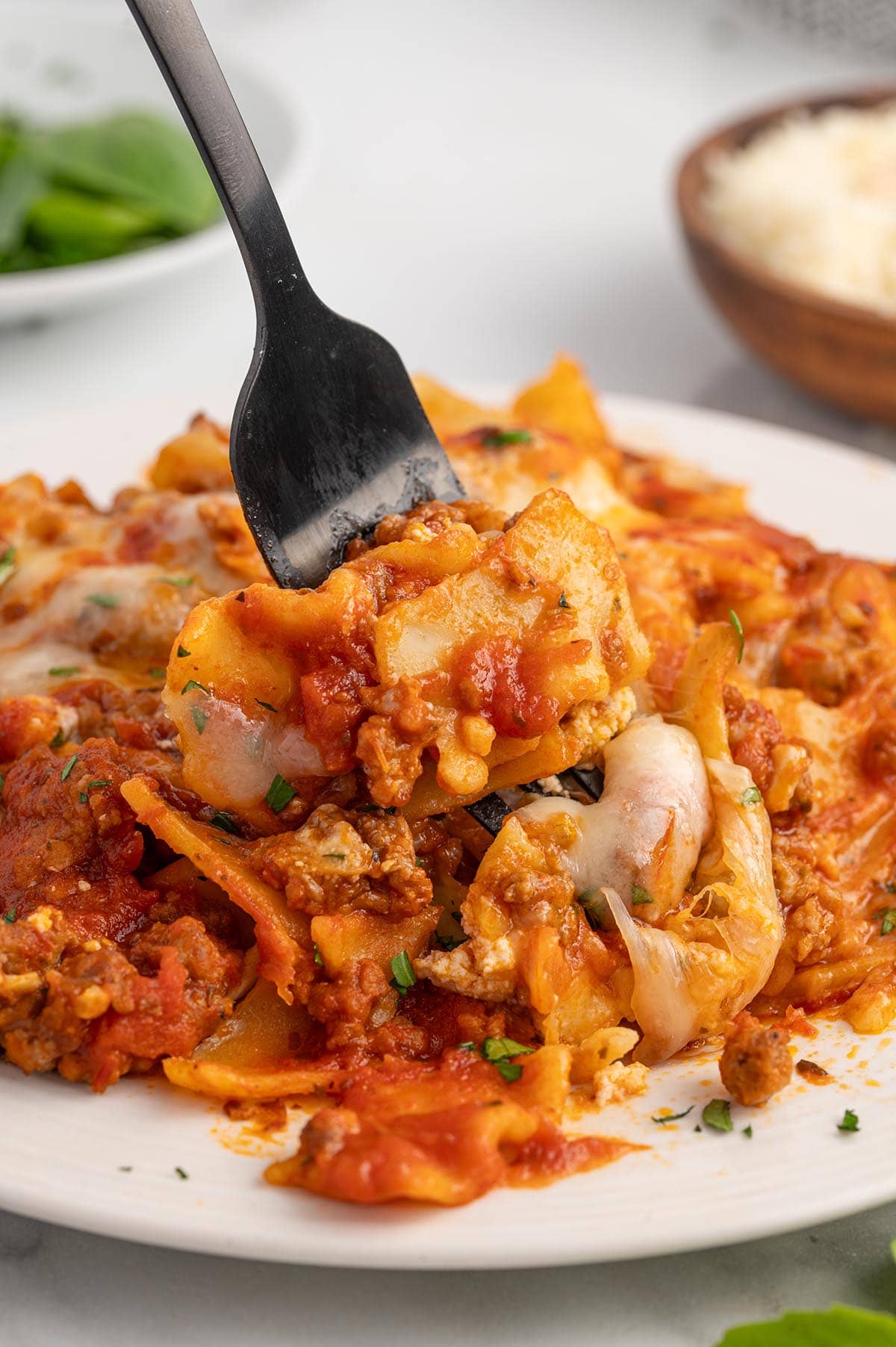 A fork lifting a cheesy, saucy bite of skillet lasagna.